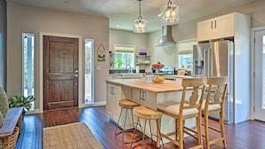 A modern kitchen with a large island, stainless steel appliances, and wooden bar stools. - Luxe Lake Arrowhead Farmhouse w/ Deck + Patio (Lake Arrowhead)