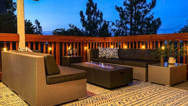 An outdoor seating area with a fire pit, sofas, and a patterned rug. - Luxe Lake Arrowhead Farmhouse w/ Deck + Patio (Lake Arrowhead)