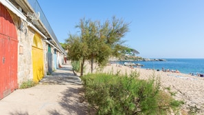 A coastal walkway leading to a beach with a row of colorful buildings.