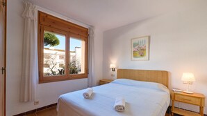 Ein Hotelzimmer mit einem großen Bett, einem Fenster mit Vorhängen, einem Nachttisch mit Lampe und einem an der Wand hängenden Gemälde.