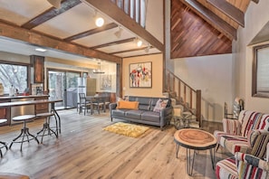 A spacious living area with a wooden ceiling, a sofa, a dining table with stools, and a staircase. - Woodsy Twin Peaks Getaway w/ Hot Tub & Views! (Twin Peaks)