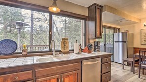 A kitchen with a large window, wooden cabinets, a stainless steel refrigerator, and a dishwash unit.
