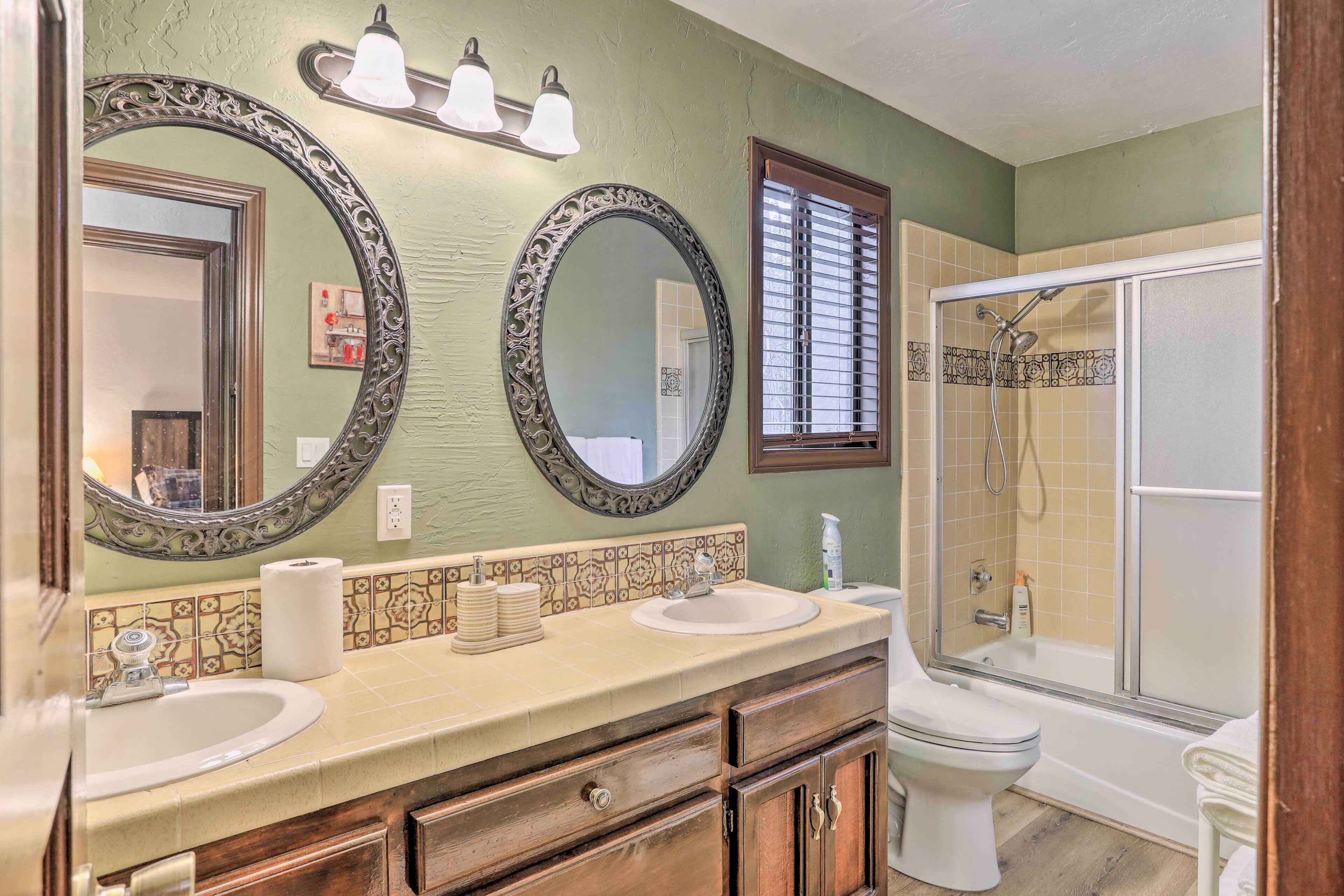 A bathroom with two sinks, a toilet, a shower, and two large mirrors.