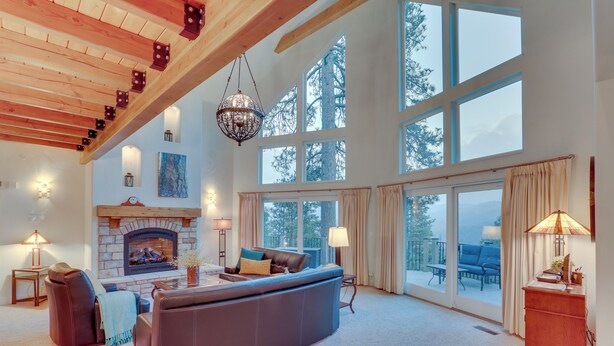 A spacious living room with a fireplace, large windows, and a cozy seating area. - Beautiful Lake Arrowhead Cabin w/ EV Charger (Lake Arrowhead)