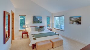 A bedroom with a large bed, two bedside tables, a window, and artwork on the walls. - Beautiful Lake Arrowhead Cabin w/ EV Charger (Lake Arrowhead)