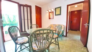 A dining area with a round table and chairs, a sofa, and a door leading to another room.