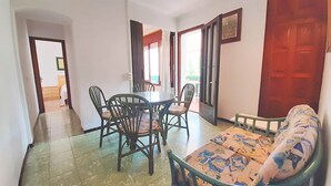 A room with a dining table and chairs, a sofa, and a wooden door.