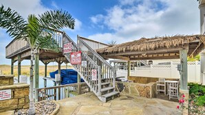 A wooden deck with a thatched roof, stone flooring, and a palm tree. - Corpus Christi Home w/ Golf Cart: Walk to Beach! (Corpus Christi)