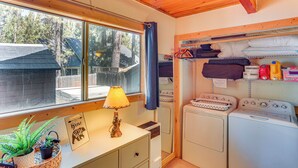A laundry room with a washing machine, dryer, and shelves with laundry supplies. - 1 Mi to Snow Summit: Big Bear Lake Cabin! (Big Bear Lake)