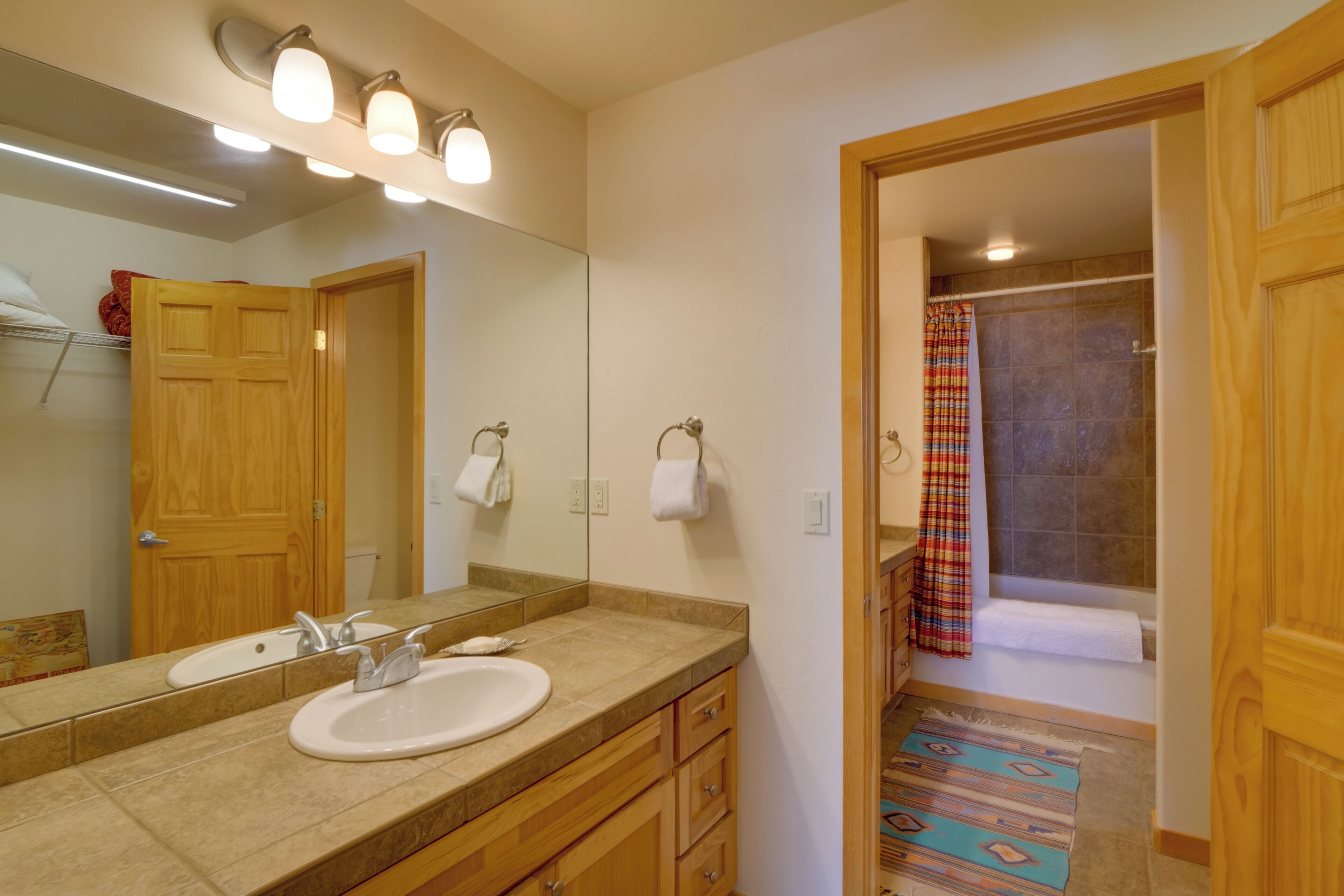 A bathroom with a wooden vanity, two sinks, a large mirror, and a shower with a curtain.