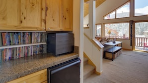 A kitchen with wooden cabinets, a refrigerator, and a countertop with books. - Slopeside Sanctuary - Penthouse < 1 Mi to Lifts! (Winter Park)