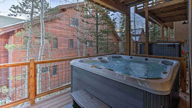 A wooden deck with a hot tub, wooden beams, and a view of a red cabin. - Mountain View Retreat, Walk to Winter Park Gondola (Winter Park)