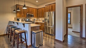 A modern kitchen with wooden cabinets, stainless steel appliances, and a bar area with stools. - Mountain View Retreat, Walk to Winter Park Gondola (Winter Park)