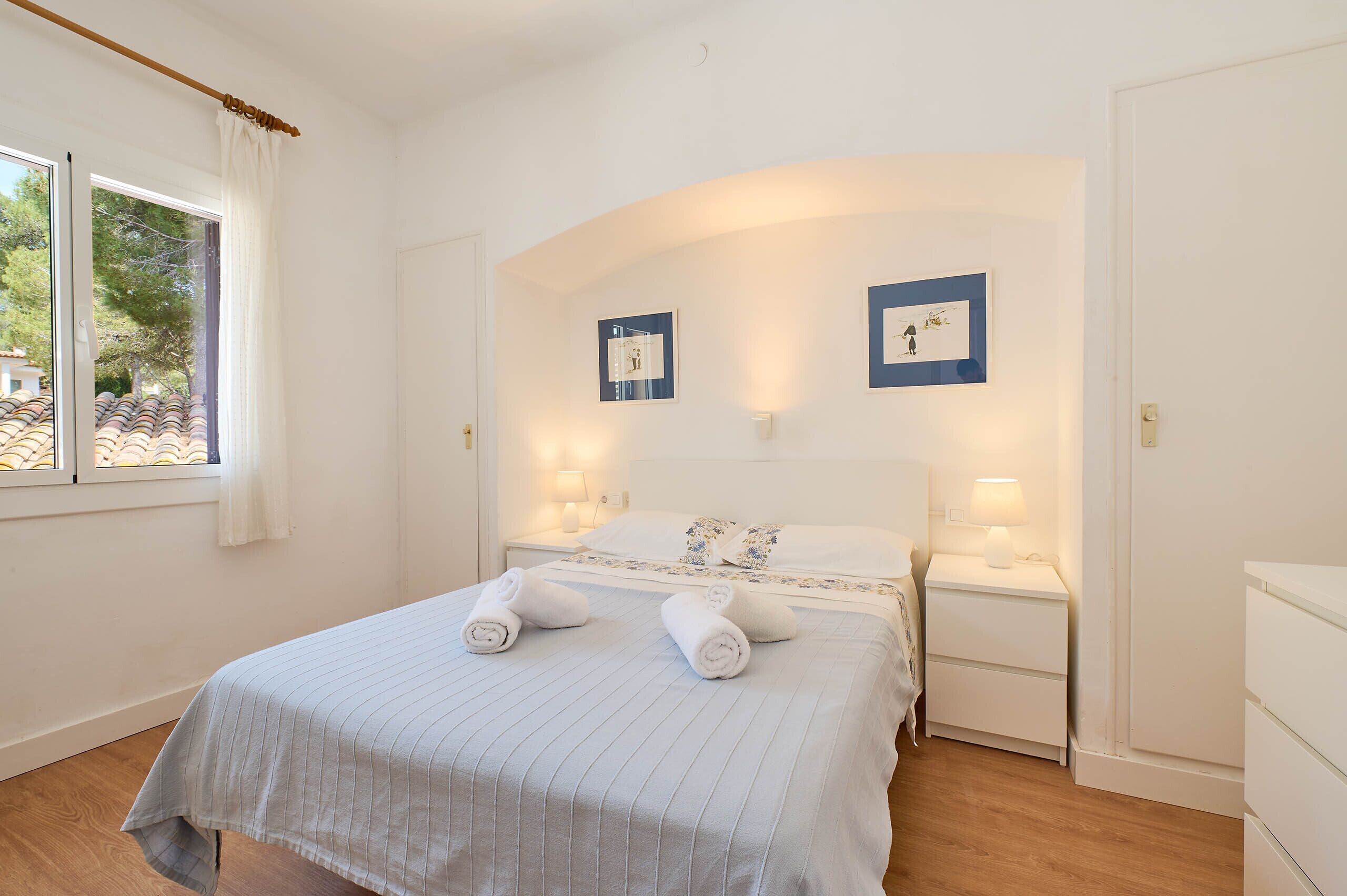 A neatly arranged bedroom with a bed, bedside tables, and a window.