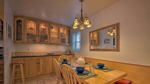 A kitchen with wooden cabinets, a dining table set for four, and a chandelier. - Avalon Escape: Everything Within Walking Distance! (Avalon)