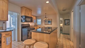 A kitchen with wooden cabinets, a central island with stools, a microwave, and a stove. - Avalon Escape: Everything Within Walking Distance! (Avalon)