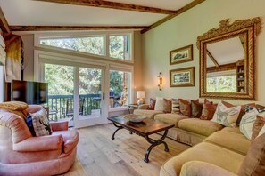 A cozy living room with a large window, a fireplace, and a dining area.