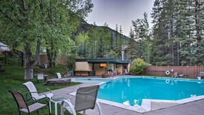 A backyard with a swimming pool, outdoor seating, and a small building with a chimney.