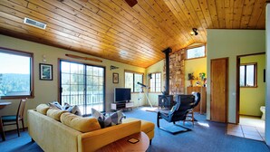 A cozy living room with a yellow sofa, a television, and a fireplace. - The Atomic Squirrel Lodge Lake Gregory Getaway! (Crestline)
