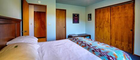 A bedroom with a bed, a wooden wardrobe, a nightstand, and a ceiling light fixture.