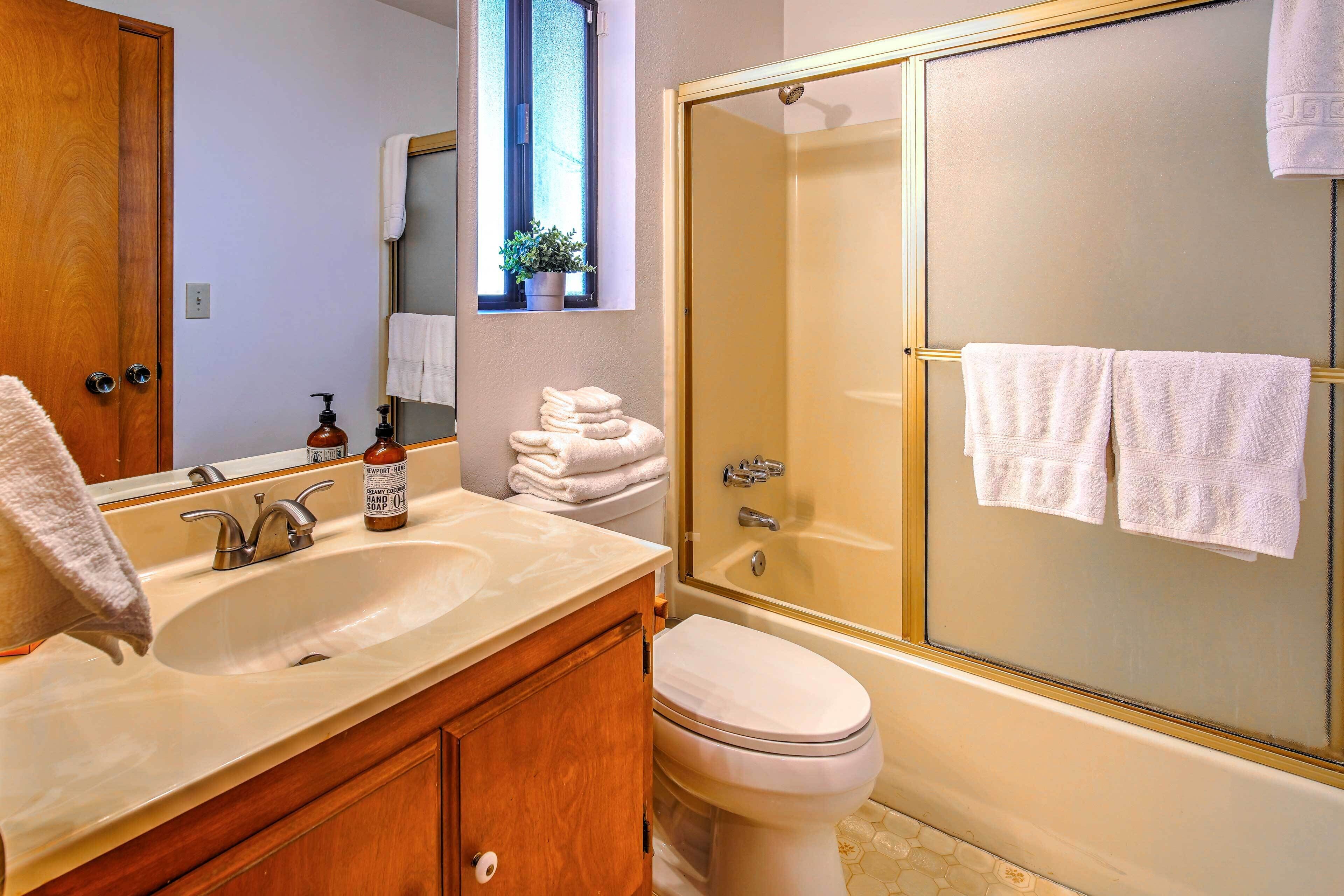 A bathroom with a sink, mirror, toilet, and a glass-enclosed shower.