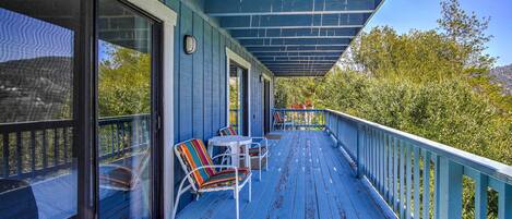 A covered porch with outdoor seating and a view of trees.