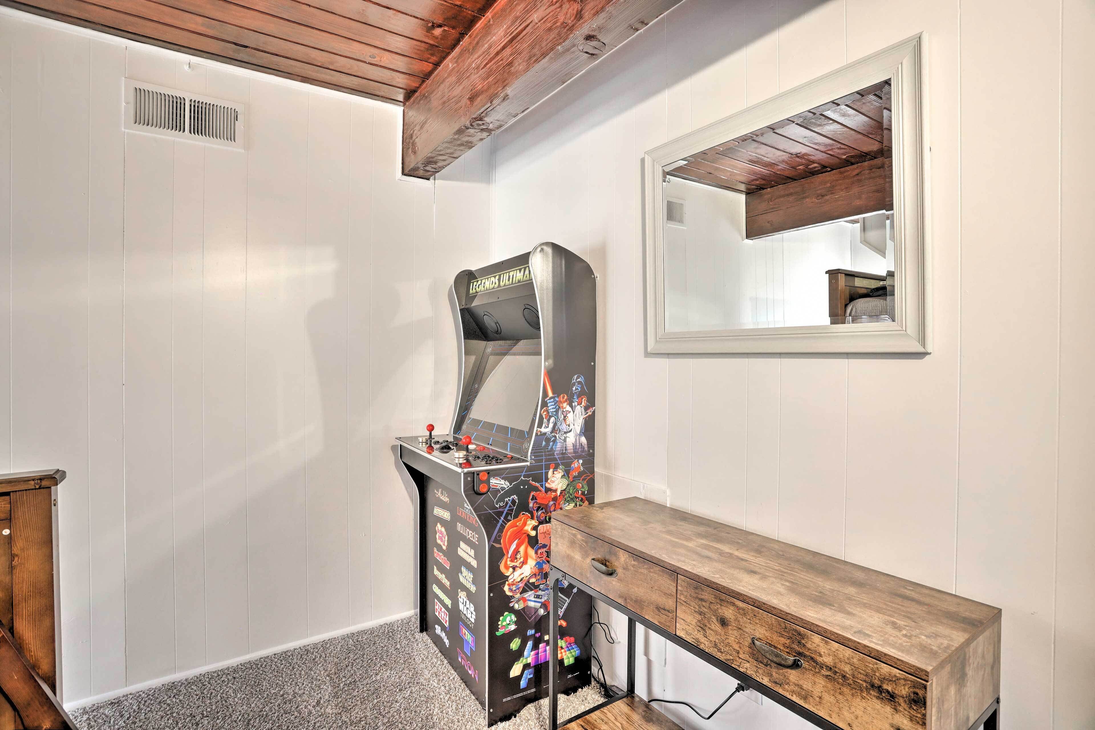 A room with a wooden cabinet, a gaming console, and a mirror on the wall.