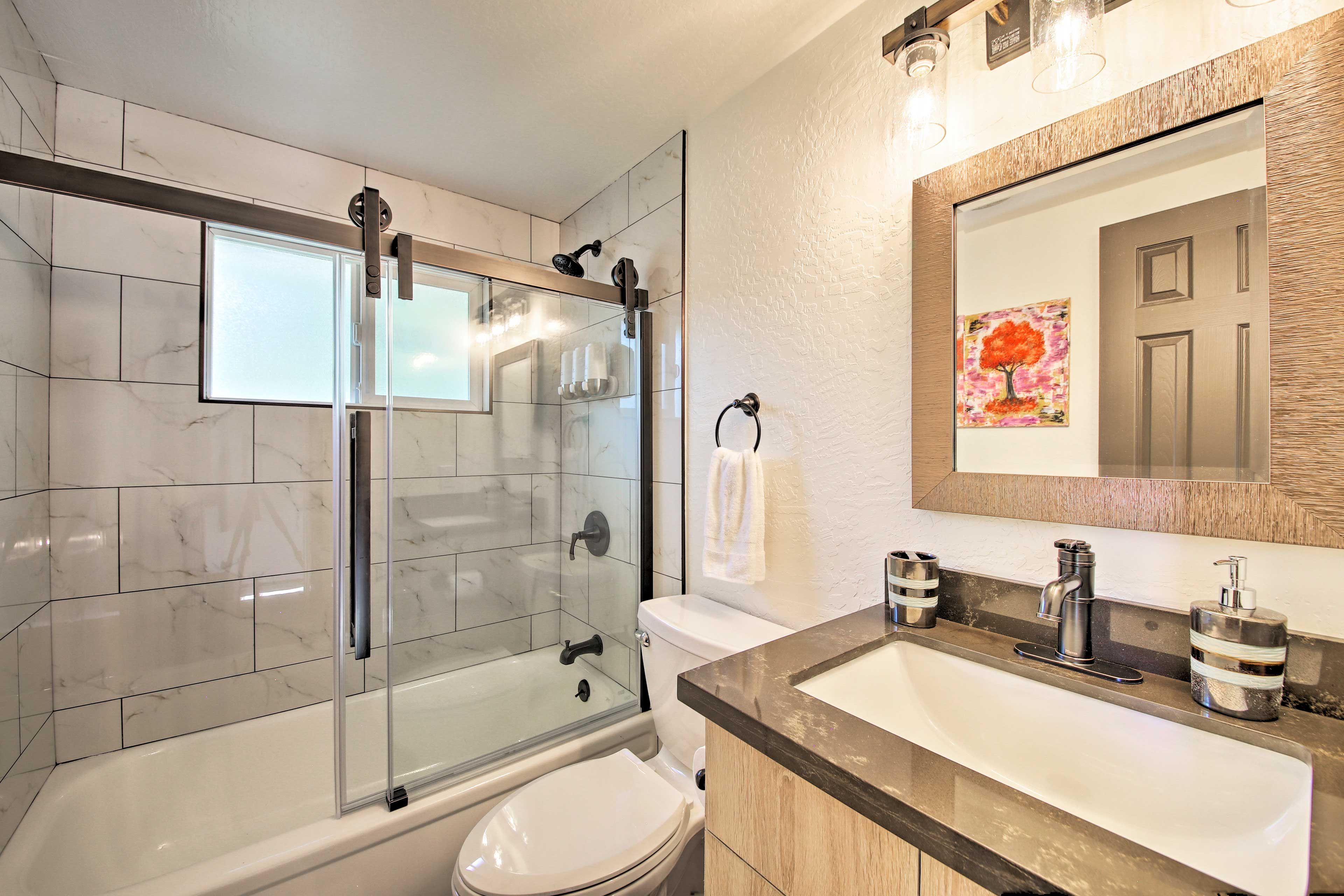 A modern bathroom with a glass-enclosed shower, a white toilet, and a sink with a wooden countertop.