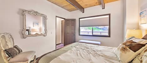 Un dormitorio con una cama grande, una silla, un espejo y una ventana con persianas.