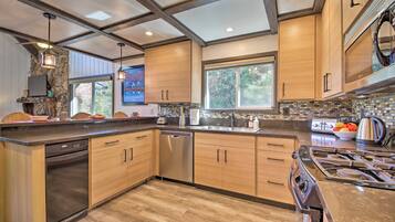 A modern kitchen with wooden cabinets, stainless steel appliances, and a large window providing natural light.