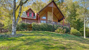 Une cabane avec des fondations en pierre, une terrasse en bois et une rambarde rouge.