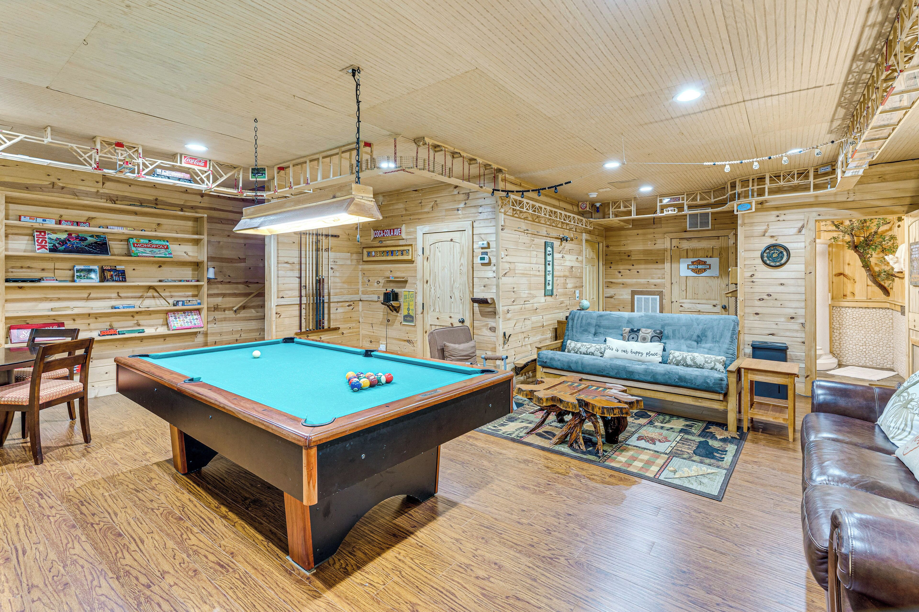 A wooden interior with a pool table, a sofa, and a coffee table.