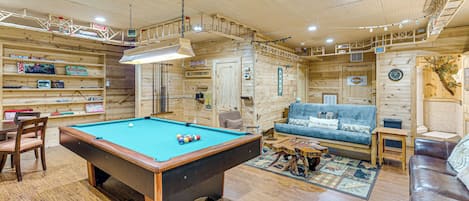 A wooden interior with a pool table, a sofa, and a coffee table.