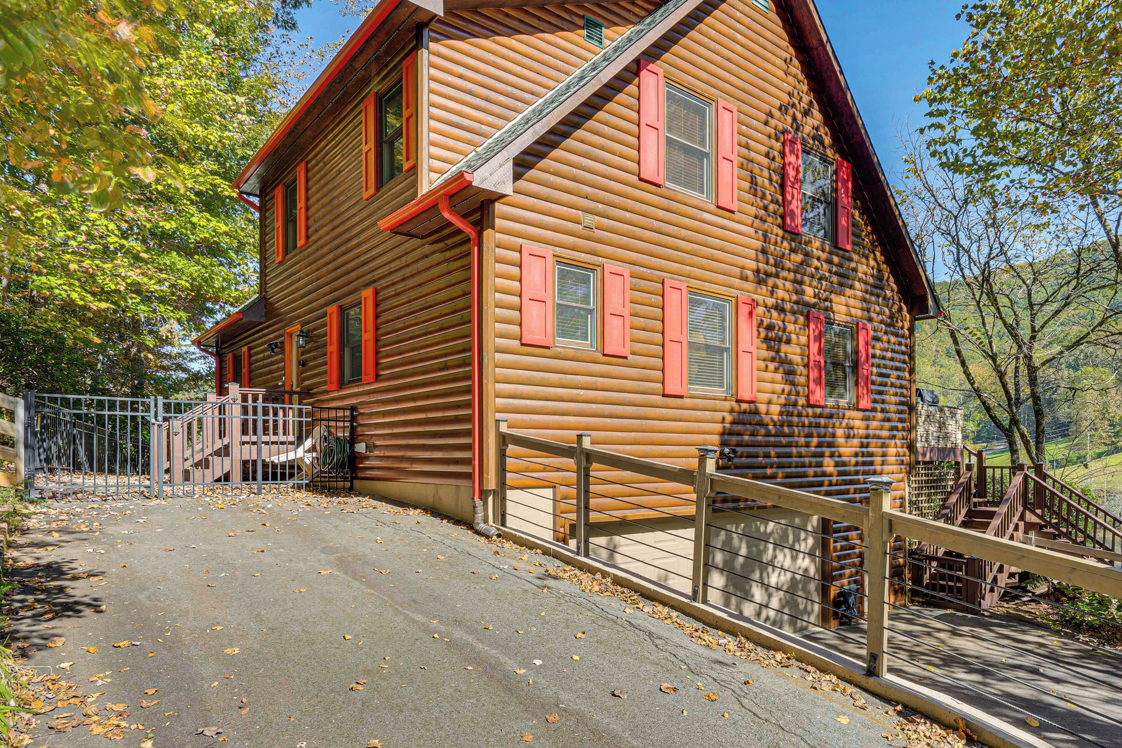A log cabin with a wooden exterior, a metal fence, and a staircase leading to the entrance.