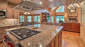 Une cuisine spacieuse dotée de plans de travail en granit, d’une cuisinière en acier inoxydable, d’armoires en bois et d’un grand îlot central.