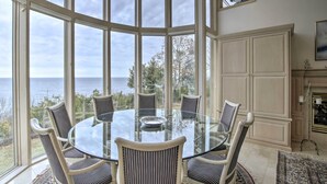 A round glass table with six chairs in a room with large windows overlooking the sea. - Grand Egg Harbor Home w/ Stunning Lake Views! (Egg Harbor)