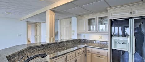 A modern kitchen with granite countertops, white cabinetry, and a built-in refrigerator.