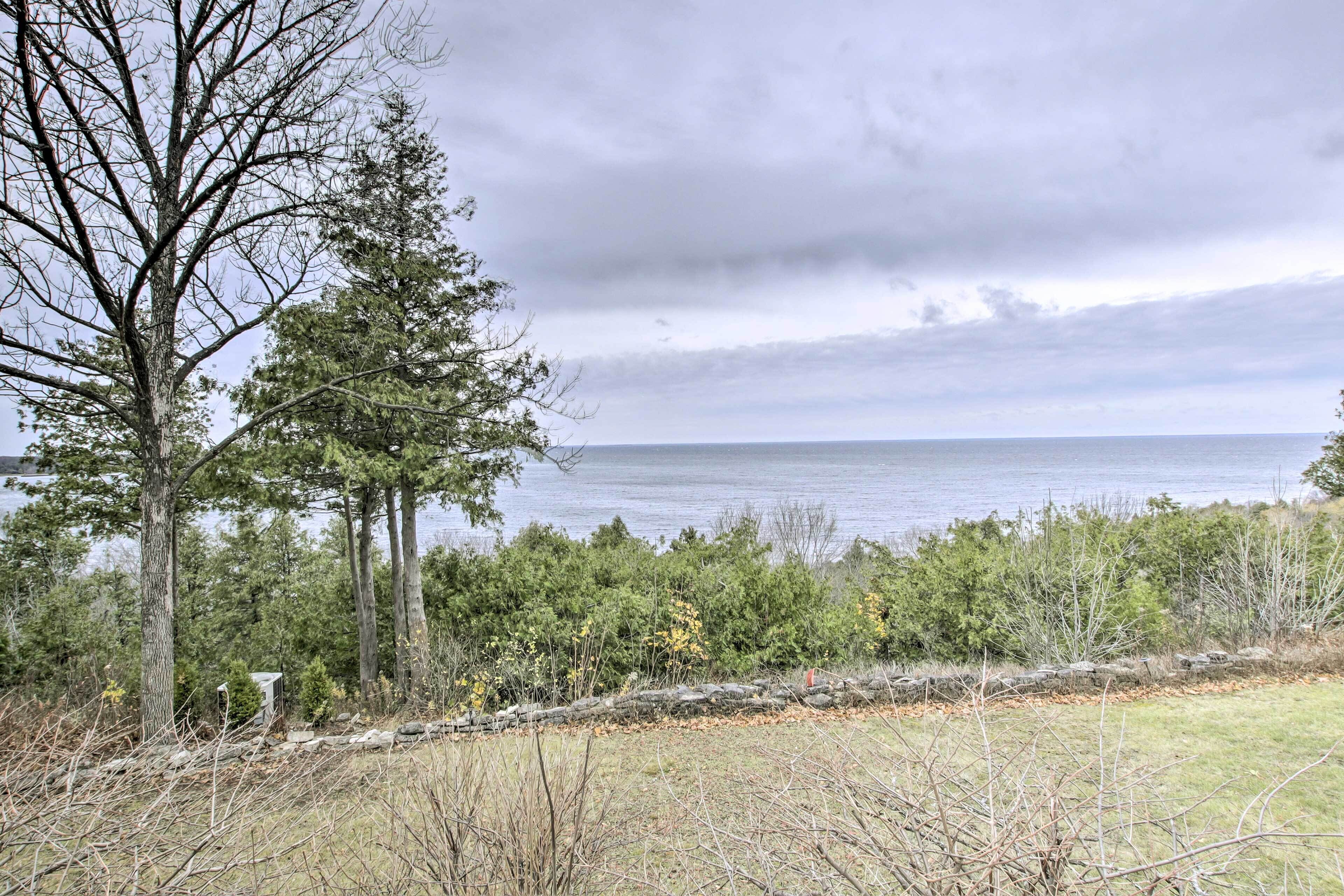 Une vue d’un lac, avec des arbres et un mur de pierre au premier plan.