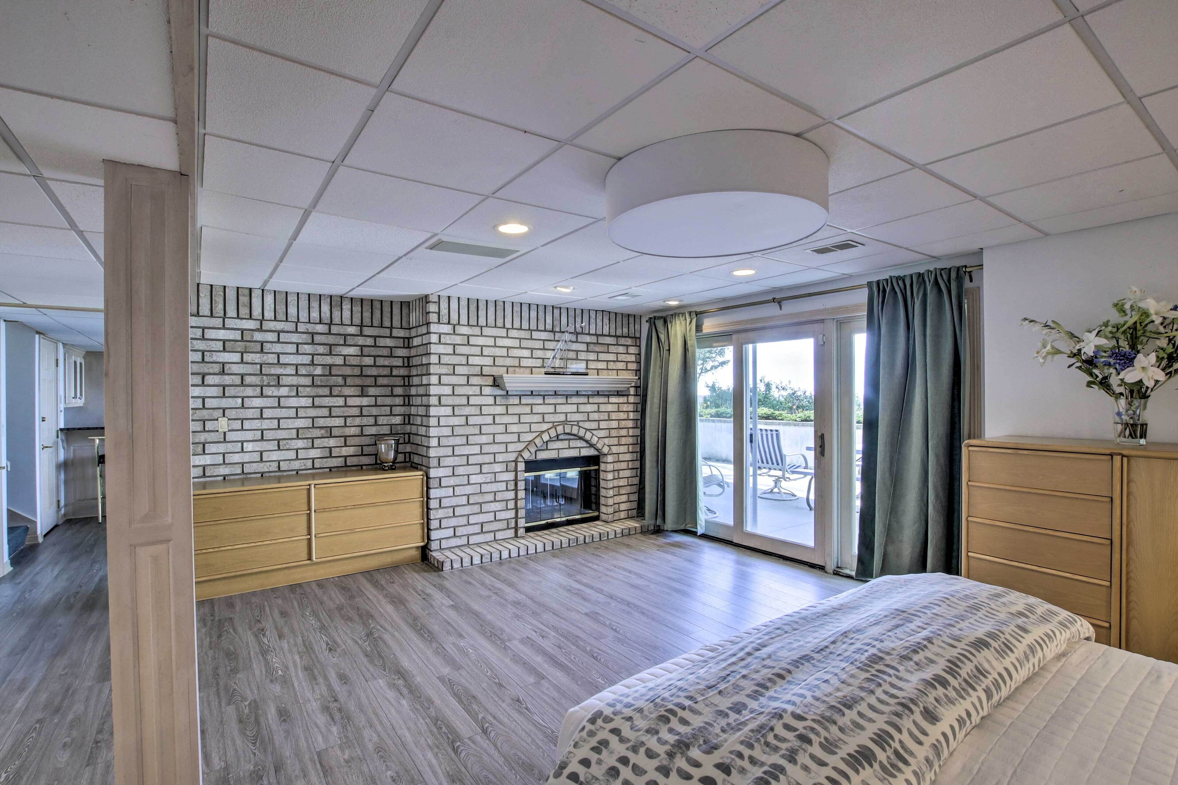 A hotel room with a brick fireplace, wooden furniture, a large bed, and a view of the outdoors.