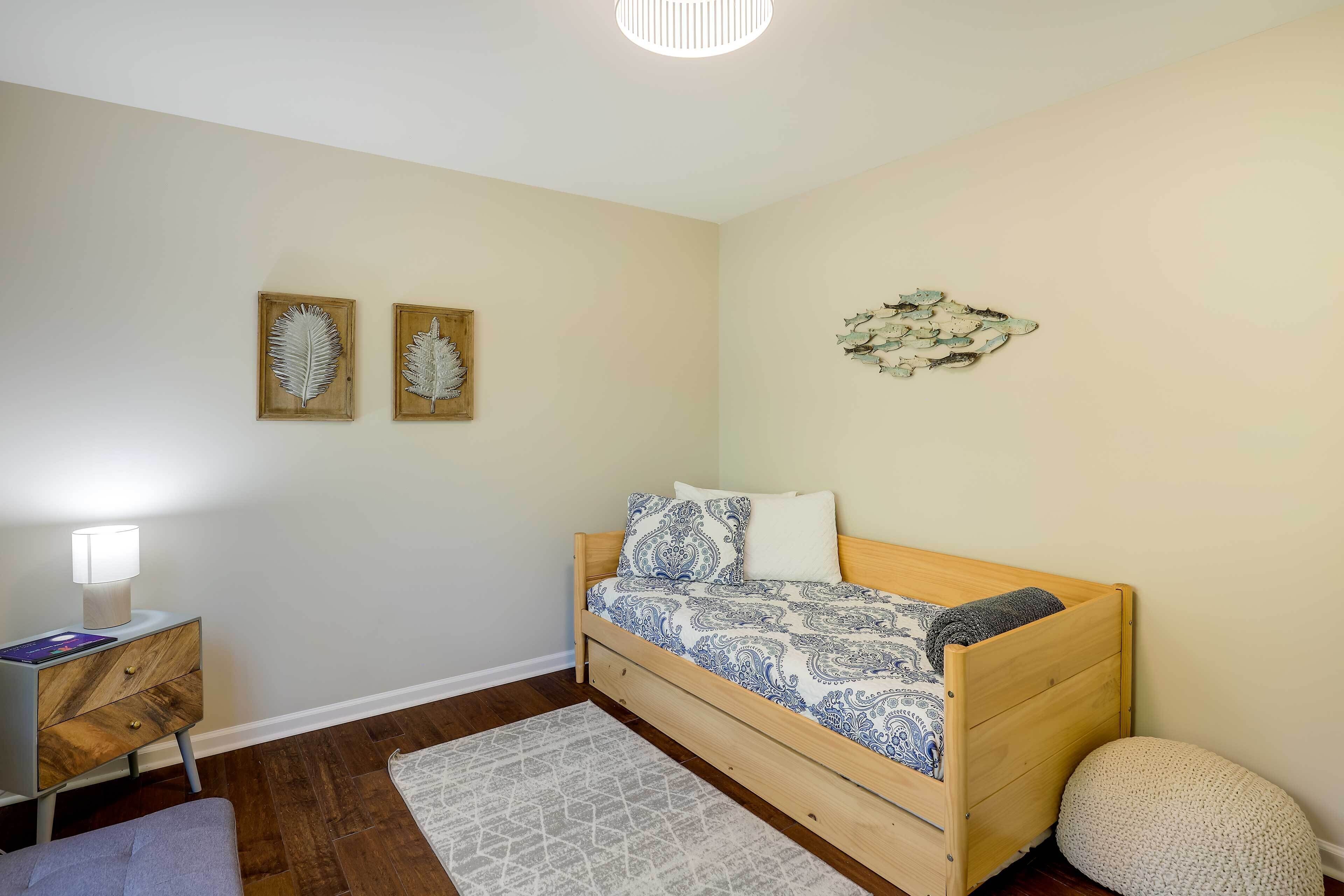 Een slaapkamer met een houten bed, een nachtkastje, een lamp, een vloerkleed en wanddecoratie.