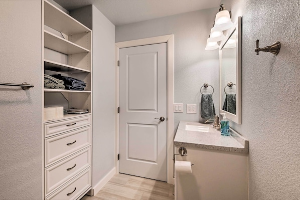 A bathroom with a white door, a sink with a soap dispenser, and a towel rack.