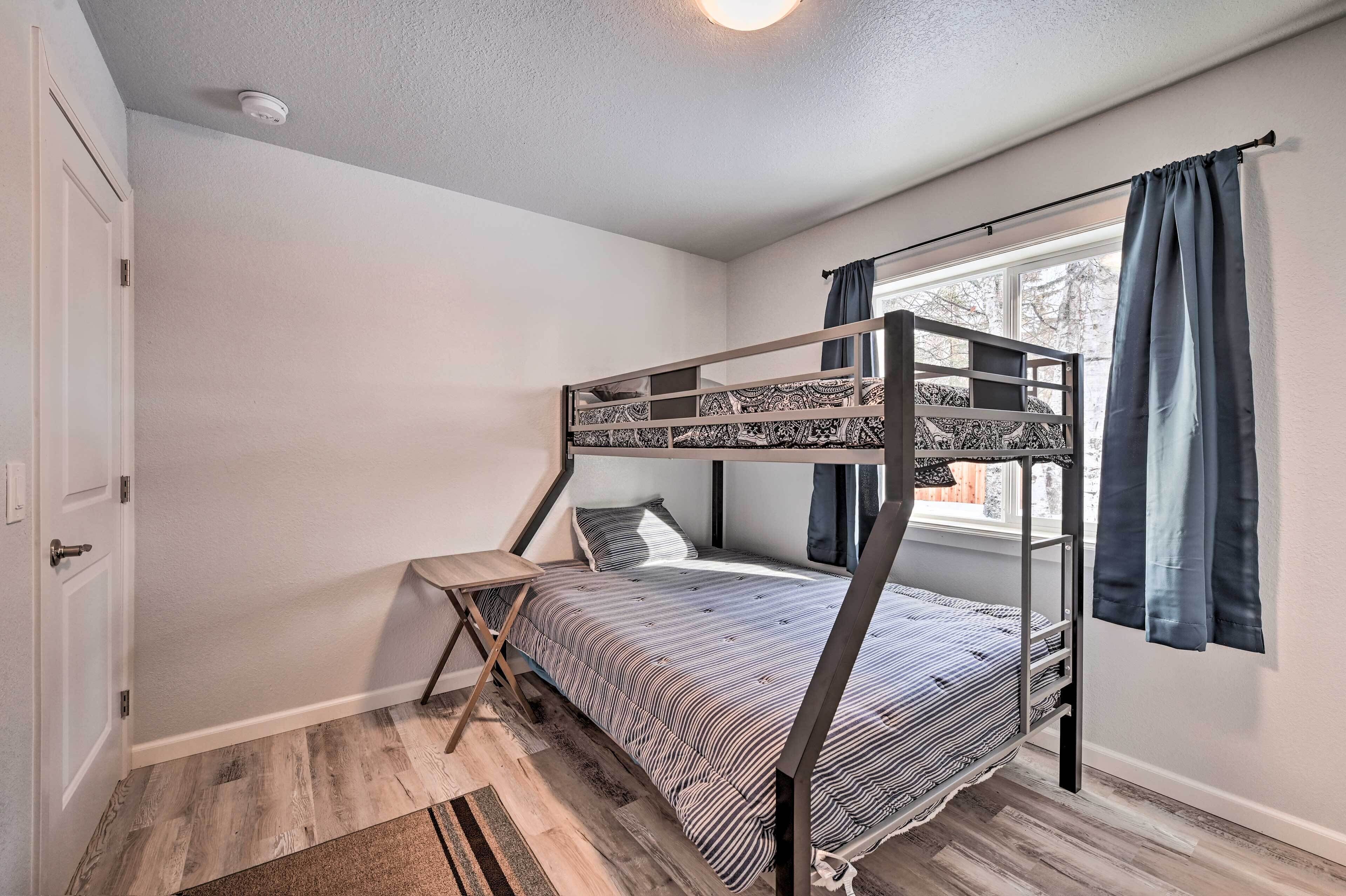 A bunk bed room with a window, a small table, and a door.