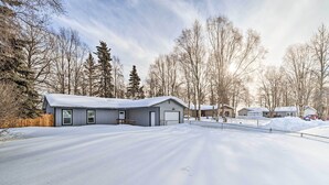 Un quartier résidentiel où les maisons sont recouvertes de neige, entourées d’arbres et surplombées par un ciel dégagé.