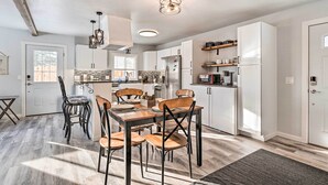 Une cuisine moderne avec des meubles blancs, une table à manger avec des chaises et un four encastré.