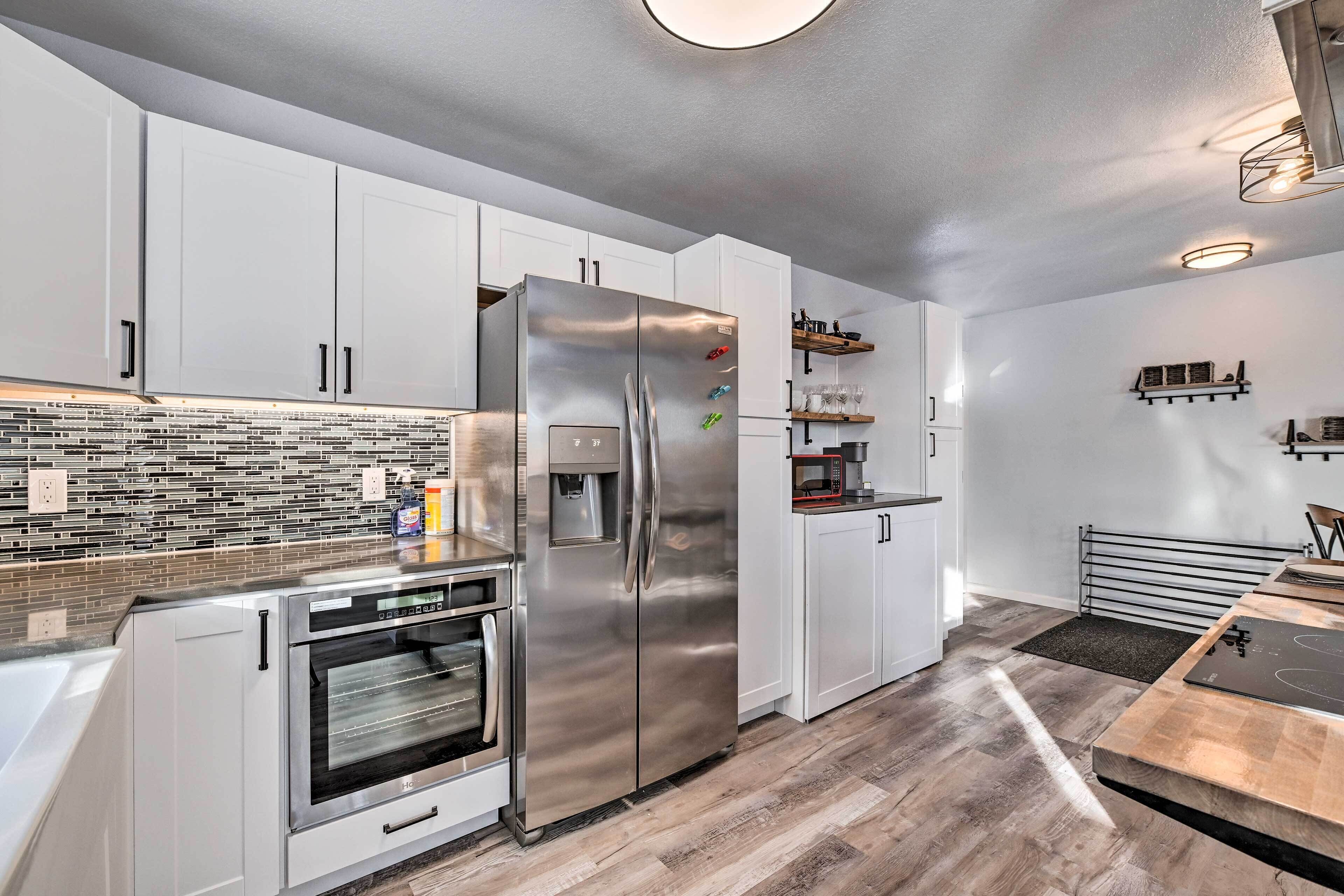 A modern kitchen with white cabinets, stainless steel appliances, and a tiled backsplash.