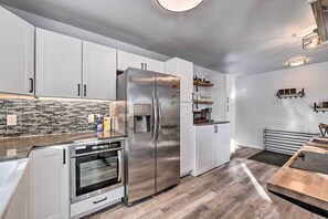 A modern kitchen with white cabinets, stainless steel appliances, and a tiled backsplash. - Kenai Home w/ Fireplace < 10 Mi to Big Eddy! (Kenai)
