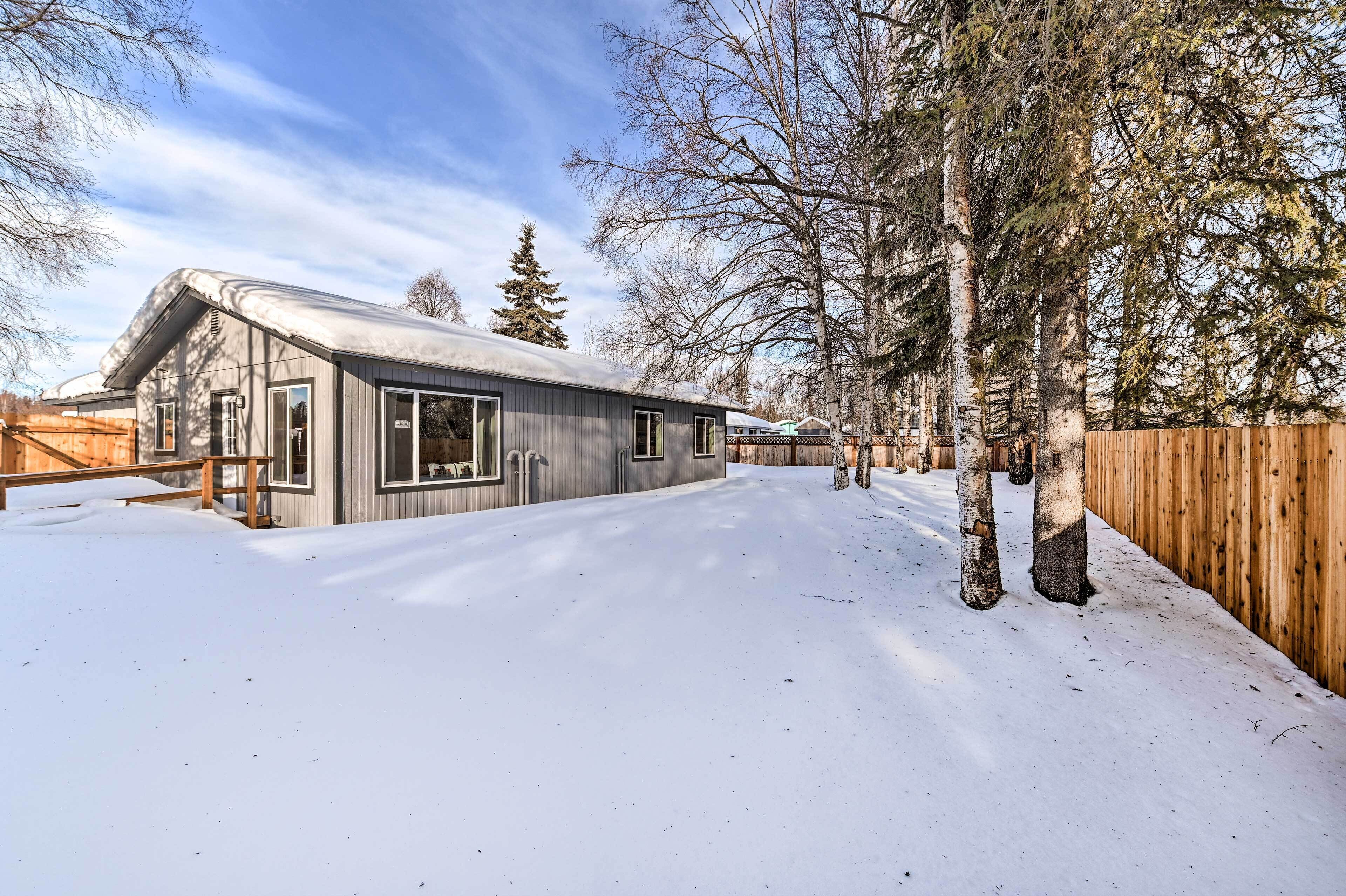 Une maison moderne avec une allée enneigée et une clôture en bois.