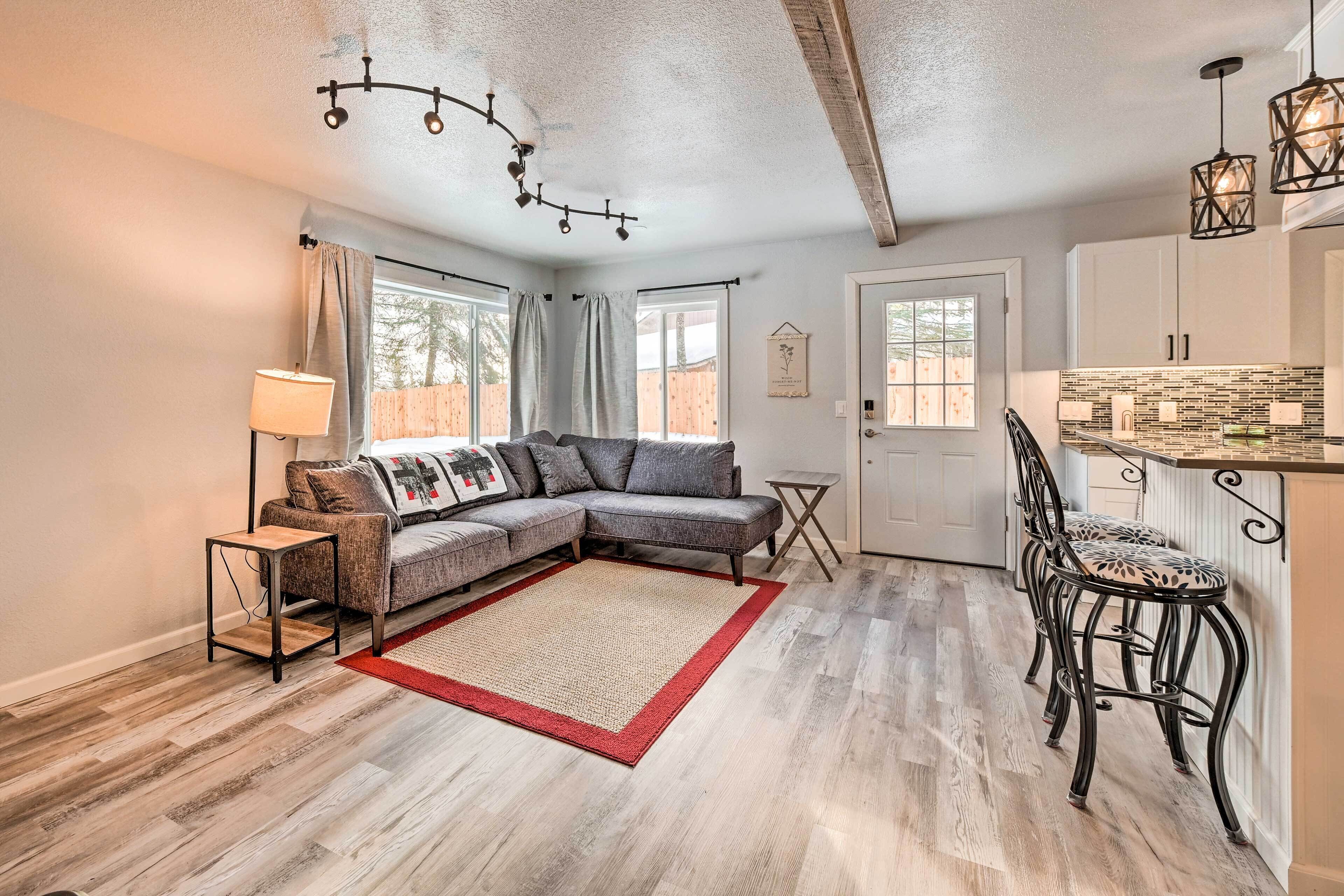 A cozy living room with a sectional sofa, a small side table, and a red rug.