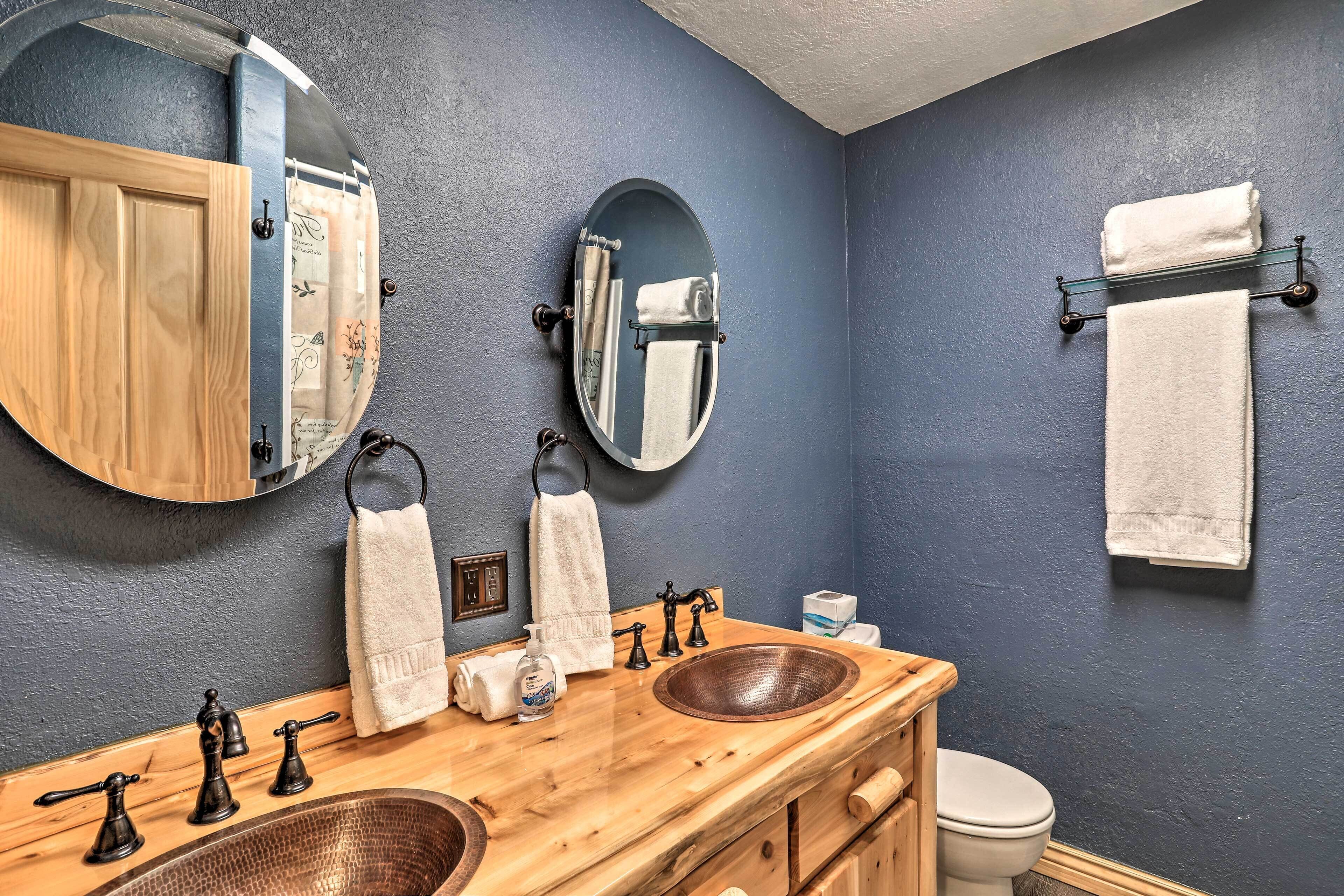 A bathroom with a wooden vanity, two sinks, a mirror, and a towel rack.