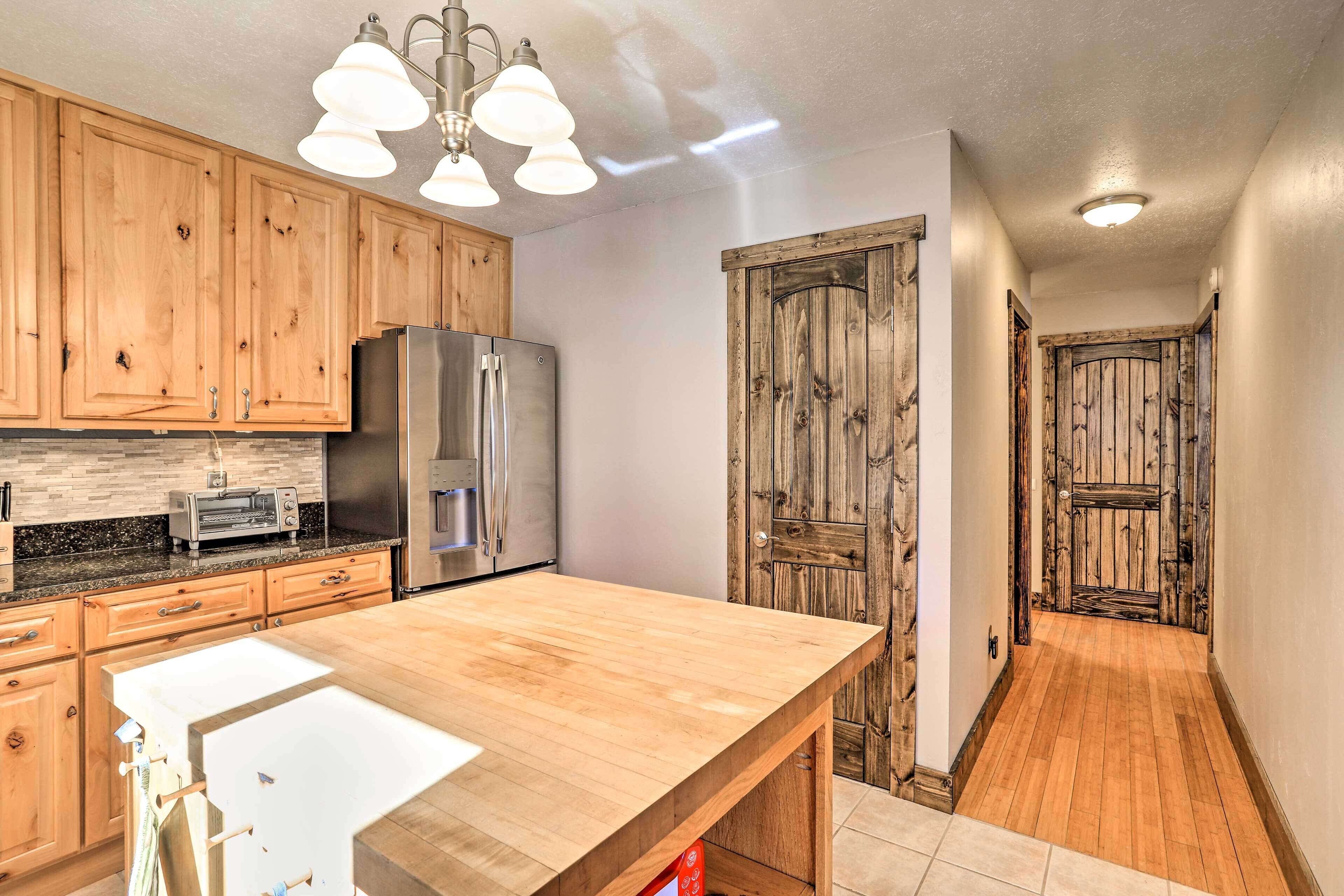 Una cocina con armarios de madera, un refrigerador de acero inoxidable, una isla de madera y una puerta rústica.
